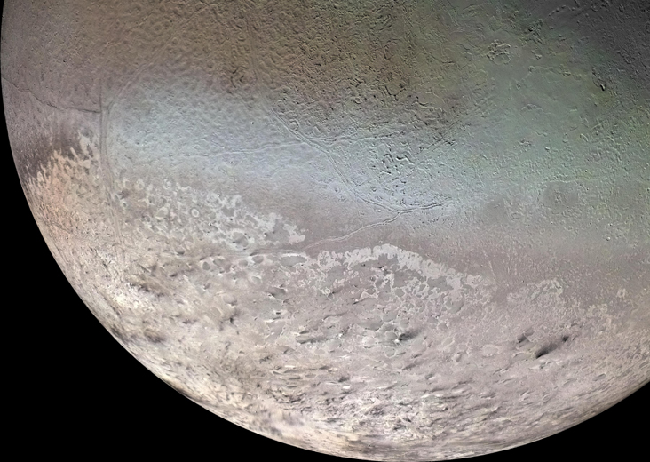 A view of Triton, a moon of the planet Neptune, showing an uneven pink surface.