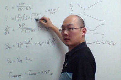 Man standing at a whiteboard covered in mathematical equations