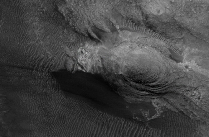 Hello Polly! Sand dunes and wind carved rock produced this piece of parrot pareidolia. Image: NASA