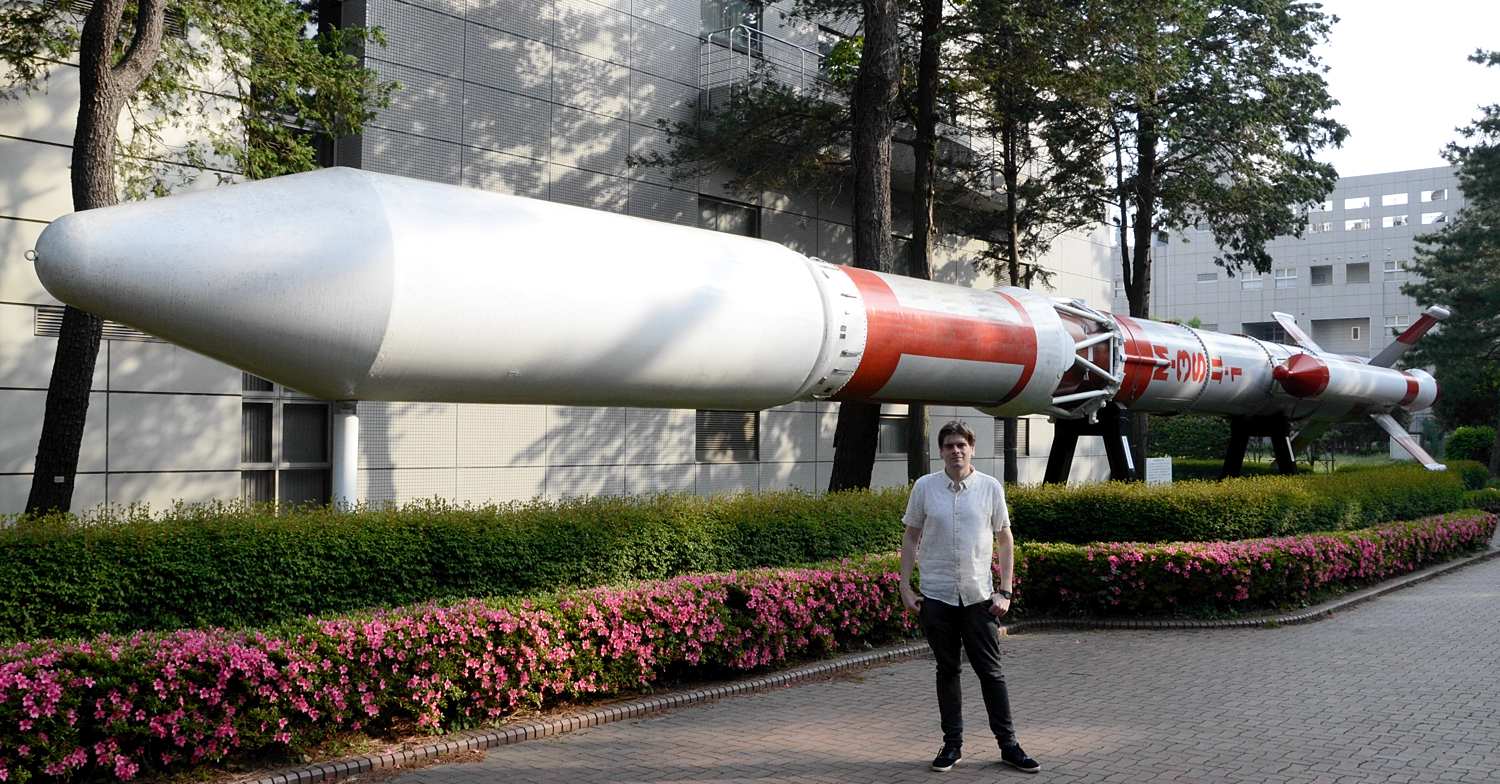 Dr Ryan Shannon in front of the M3 launch vehicle at JAXA Sagimihara campus.