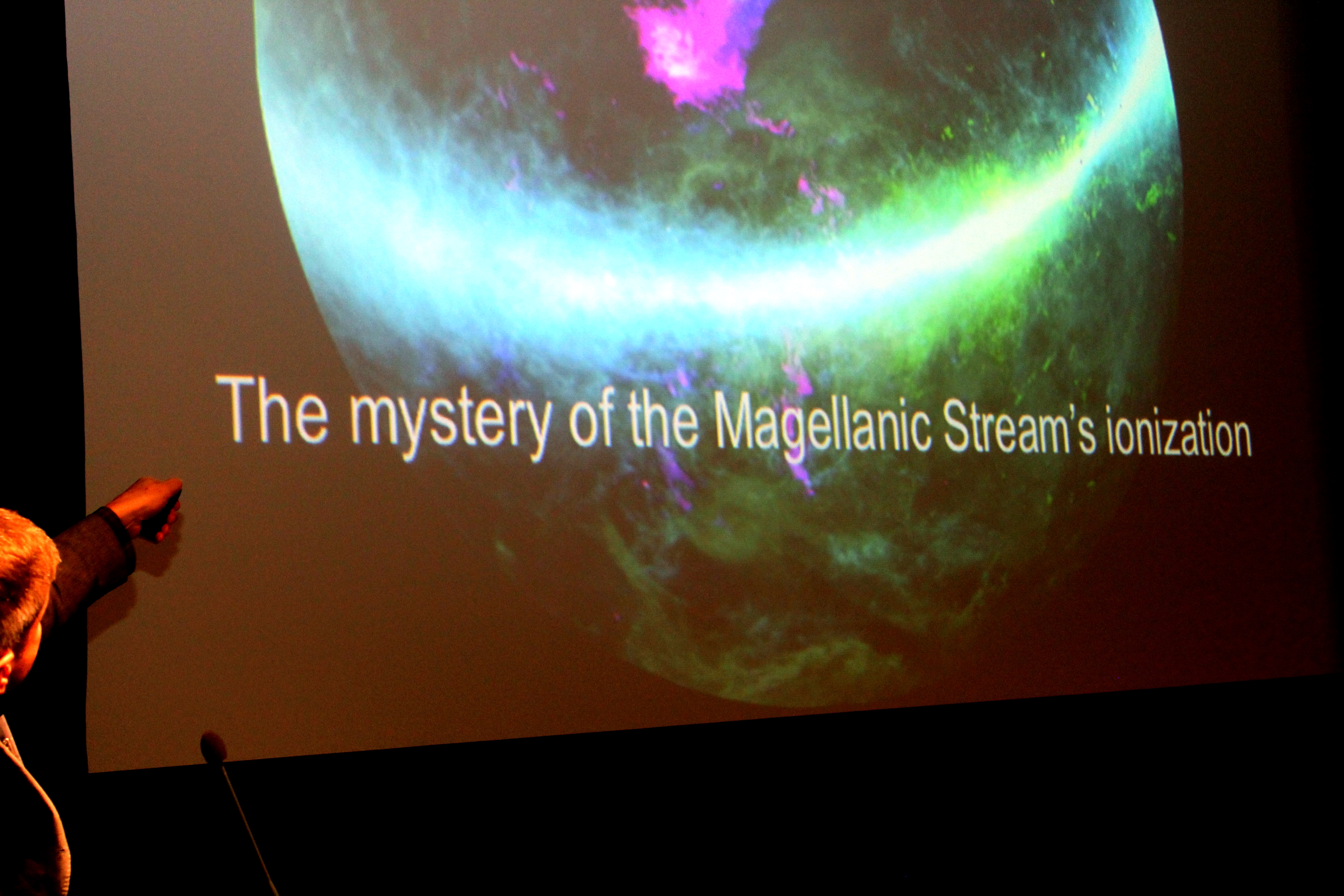 A arc of coloured light, with words underneath: "The mystery of the Magellanic Stream".