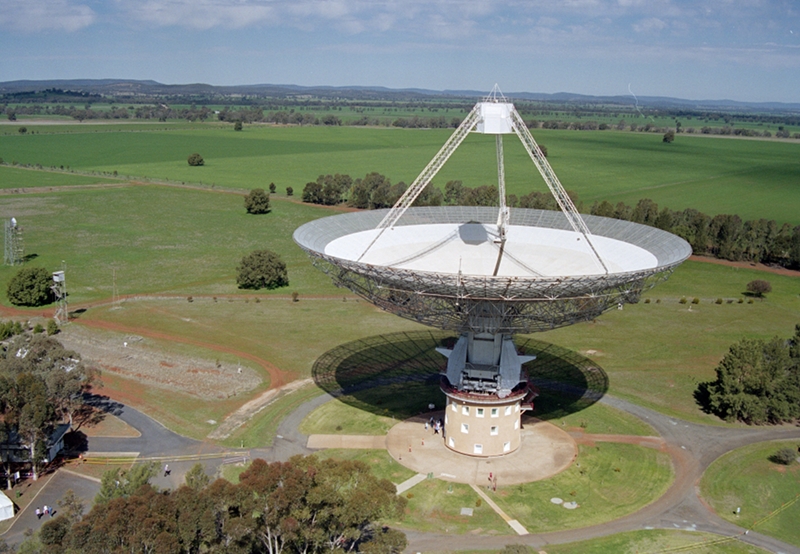 The Parkes radio telescope standing in green paddocks, seen from the air.