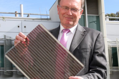 Professor Andrew Holmes holding a flexible solar cell the size of an A3 sheet of paper.
