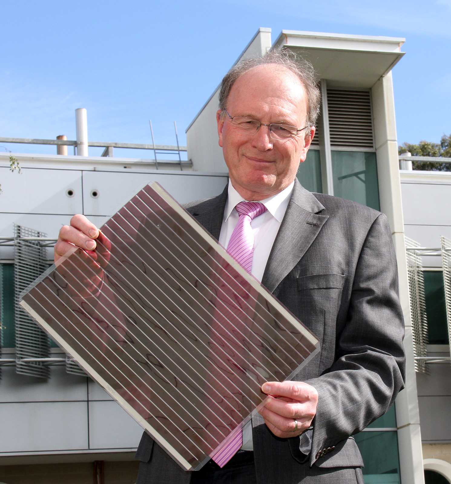 Professor Andrew Holmes holding a flexible solar cell the size of an A3 sheet of paper.