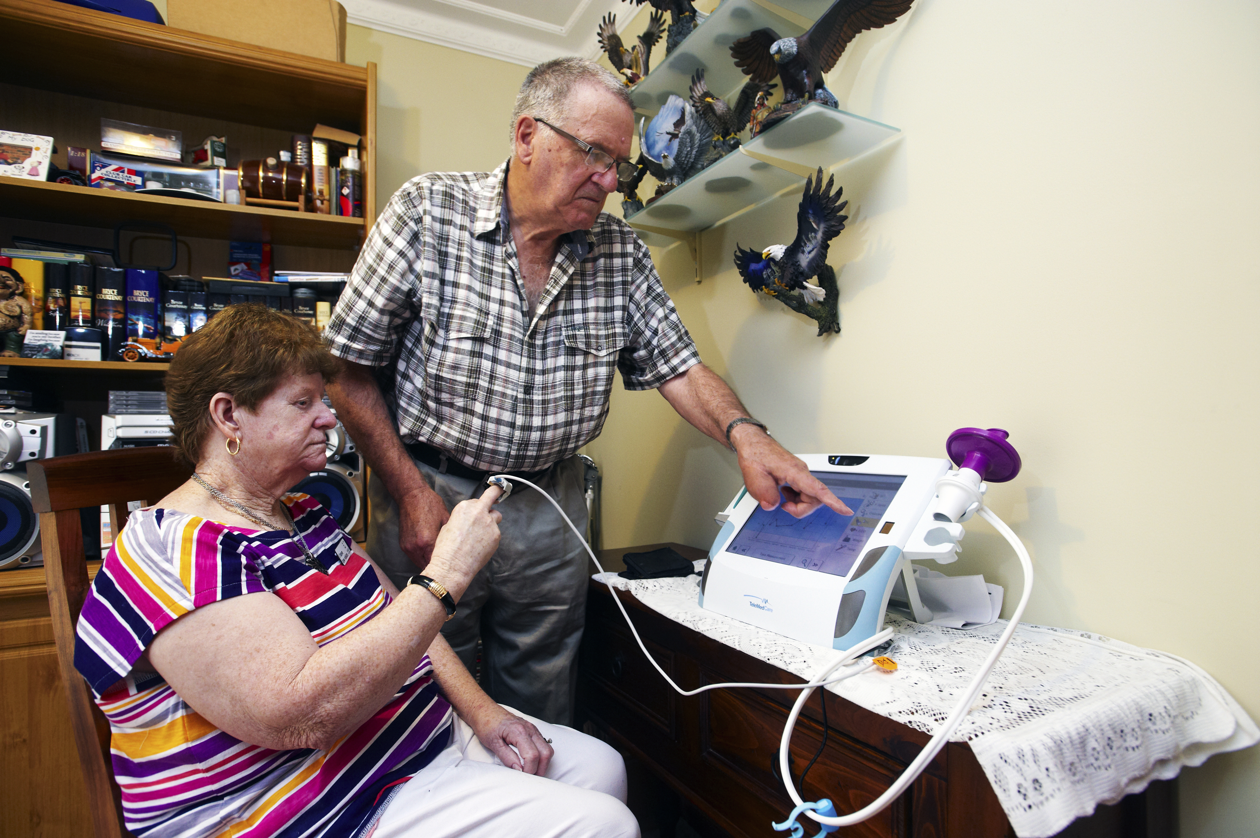 Bill helps Janice record her blood oxygen levels using the telehealth home monitoring system.