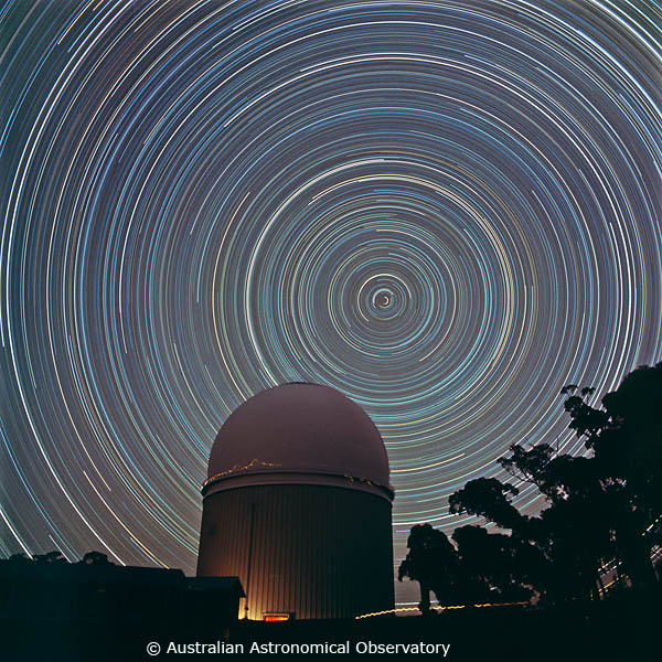 Star trails - bright concentric circles in the night sky - with a dome-shaped building in the foreground. 