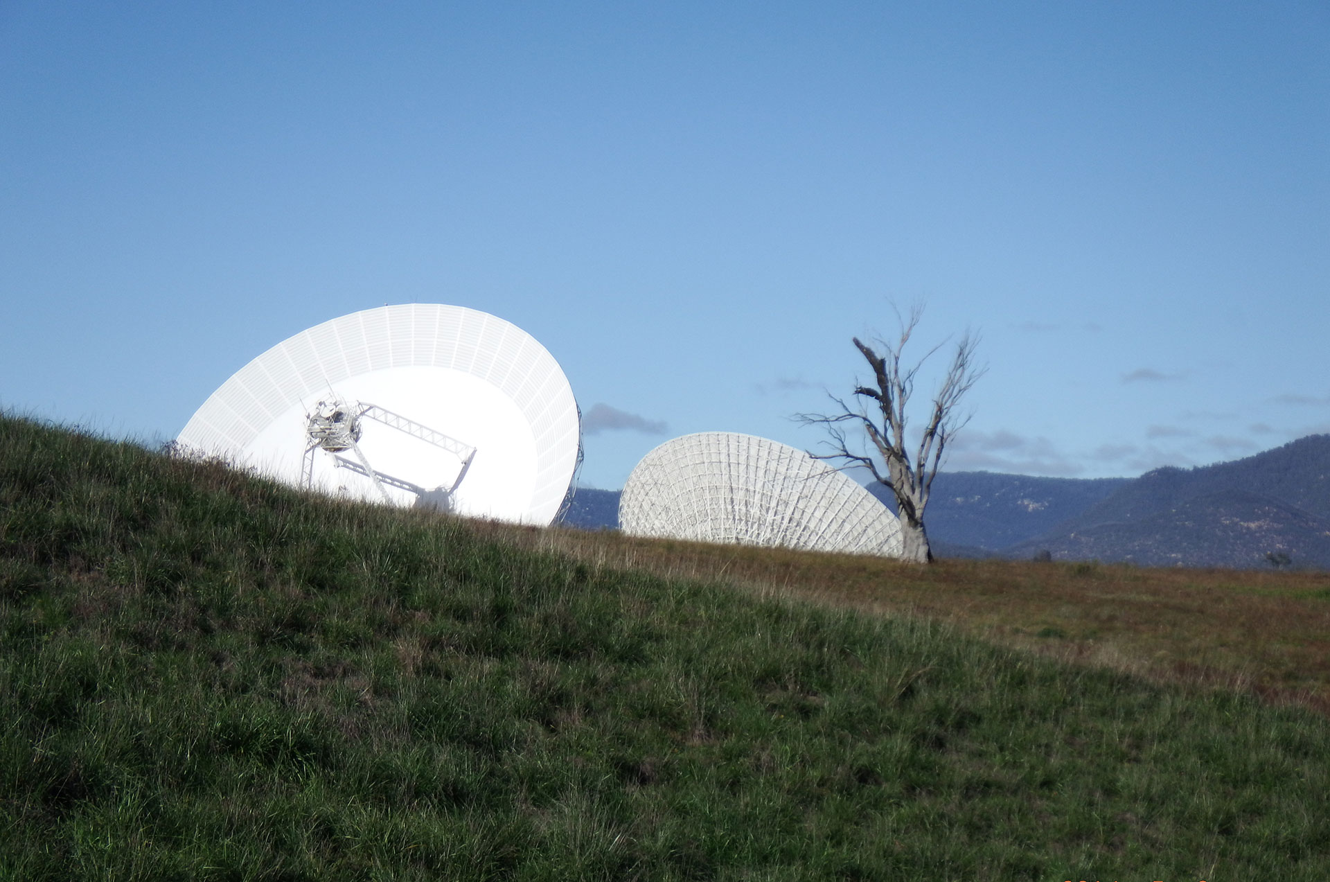 DSS34 (left) and DSS43 peak above the ground in this view from the new antenna construction area.