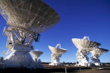 Five white telescope dishes on a bright, sunny day