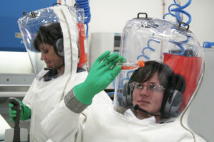 two female scientists conducting experiment in lab, fully suited in fully enlcosed biocontainment suits