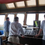 Captain Mike Watson (r) studies the seafloor maps as Colin Woodroffe (middle) looks out to sea (image MNF + Bruce Barker)