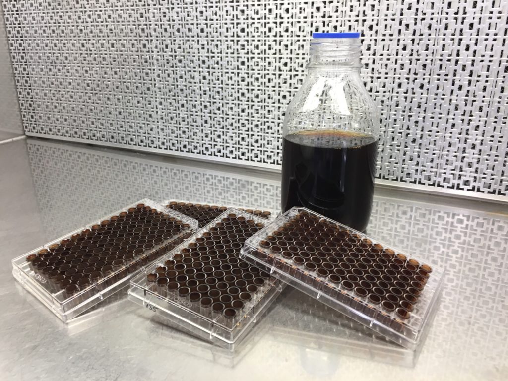 Samples of a bown coating on plastic moulds and a jar with a dark bown liquid in it
