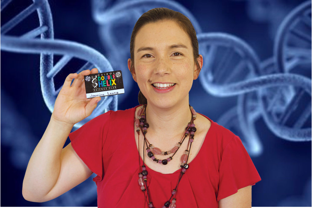 A woman in a red shirt holding a card for the Double Helix science club