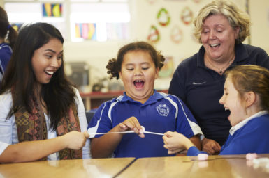 A STEM professional, teacher and two students participating in a science activity