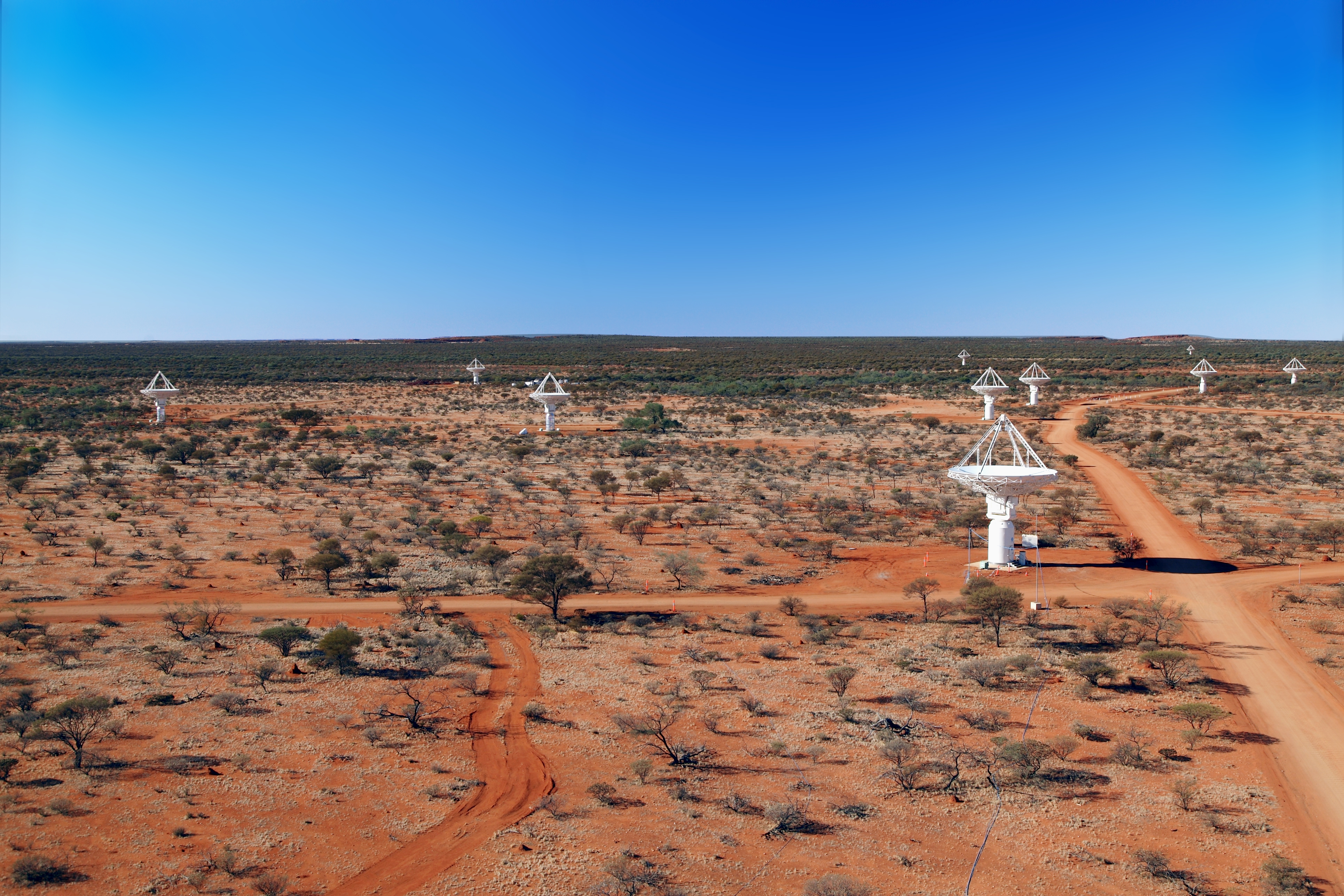 Wide area photograph of semi-arid Western Australia with ten white telescopes shown.
