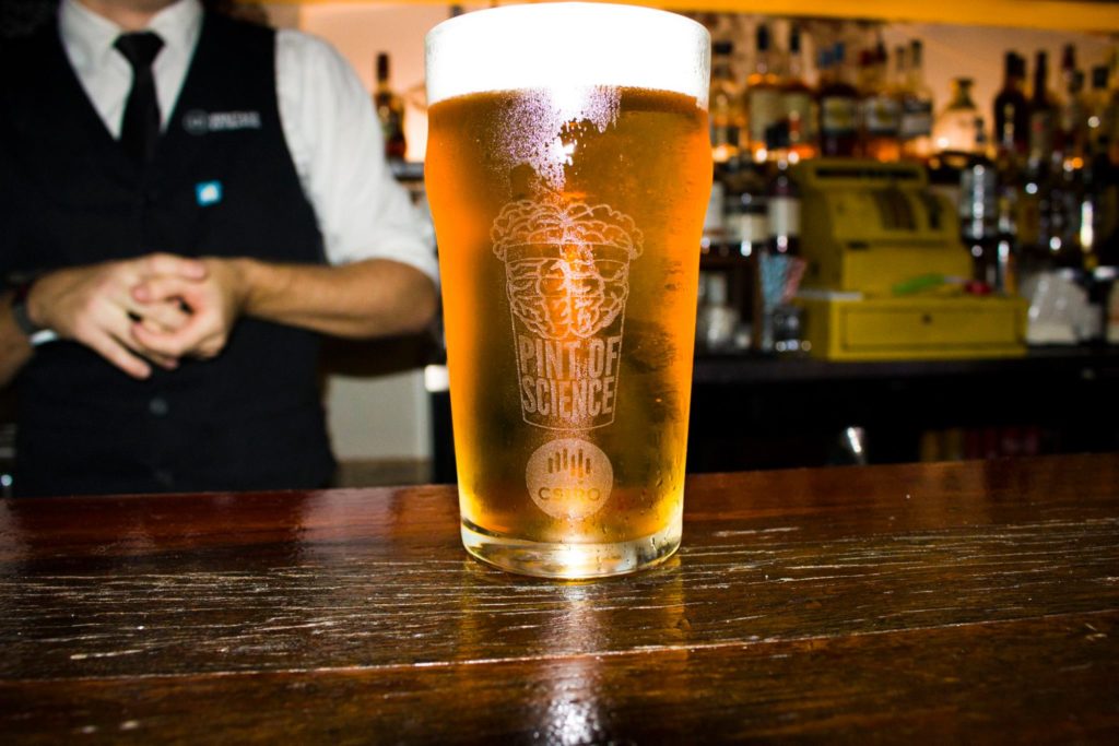 a pint glass of beer on a bar