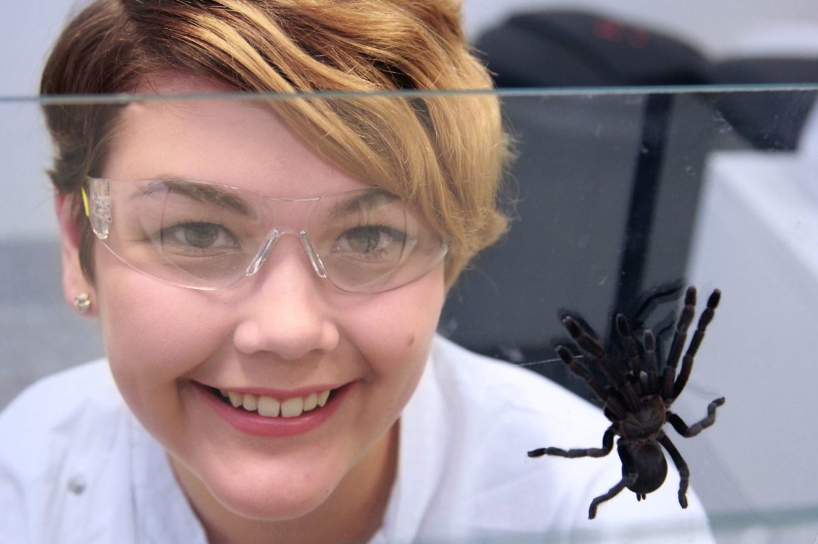 Samantha standing next to a spider in her lab