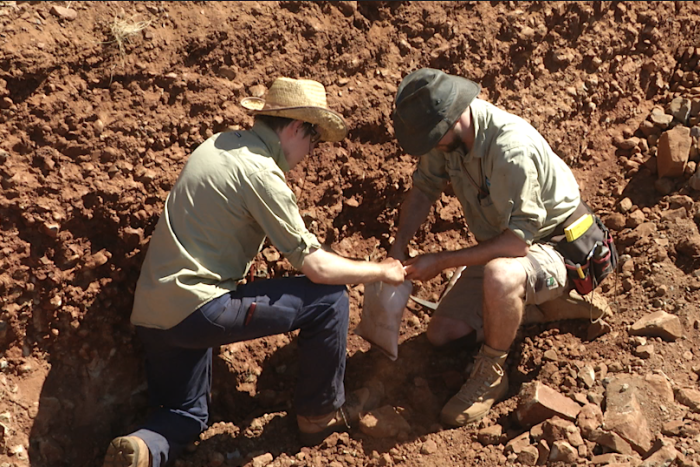Two men take samples from rock and dirt in the Pilbara