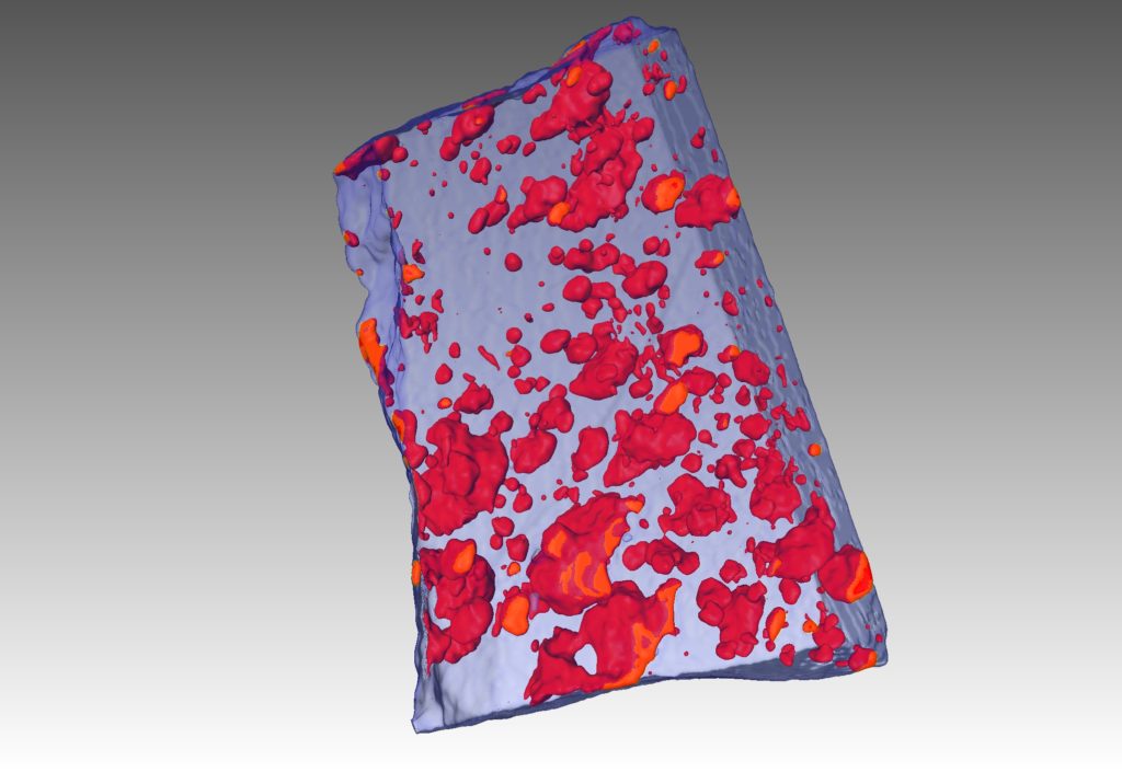 An X-ray tomography image (CT scan) of an ore sample showing frozen droplets of sulfide liquid as red blobs