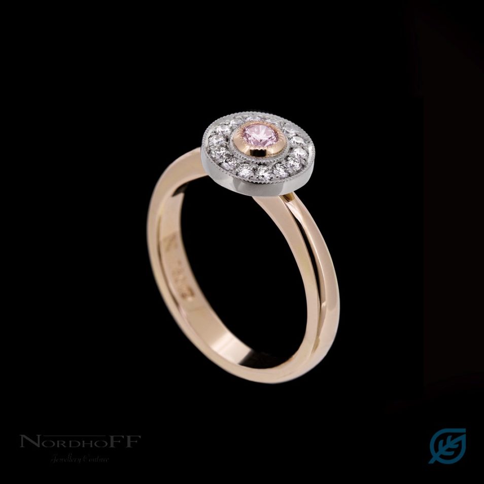 Gold ring featuring a circle of white diamonds around a pink central diamond