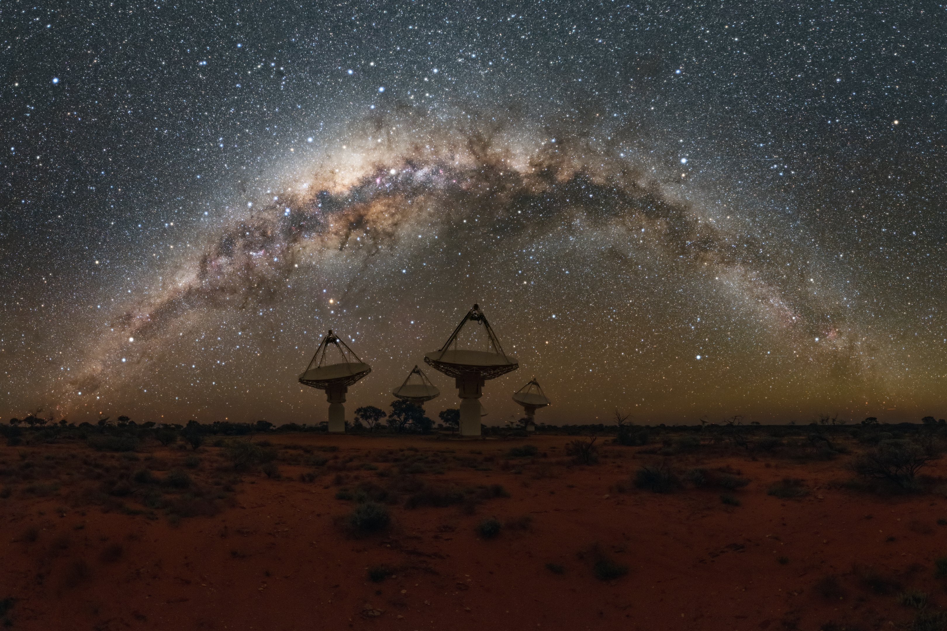 telescope dishes in an open outback landscape with the milky way above