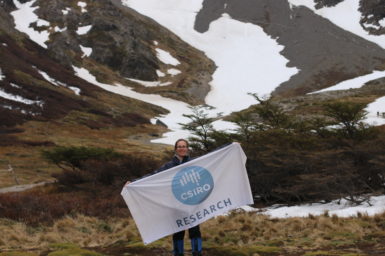 Researcher Clothilde Langlais holding a CSIRO research flag with snow in the background