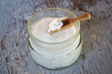 A jar of coconut oil with a wooden spoon.