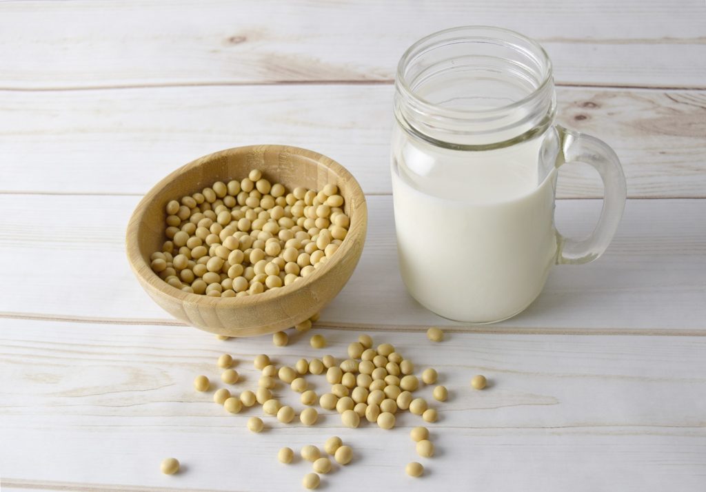 A bowl of soybeans next to a jar of milk