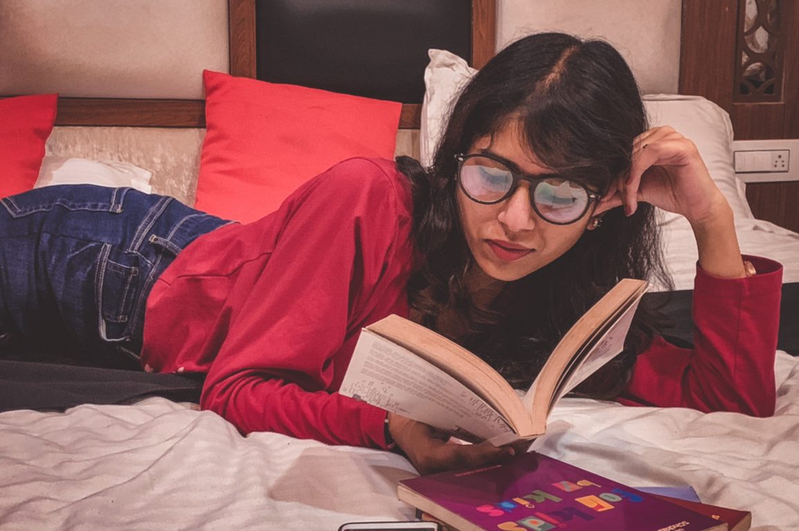 person lying on a bed reading a book
