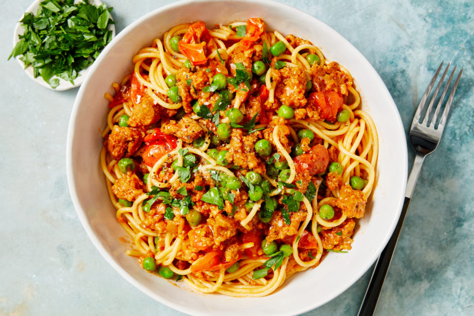 Plant-based Summer Ragu with Tomatoes and Pees with spaghetti in white bowl