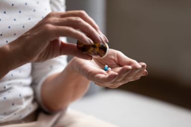 A woman pouring pills into her left hand.