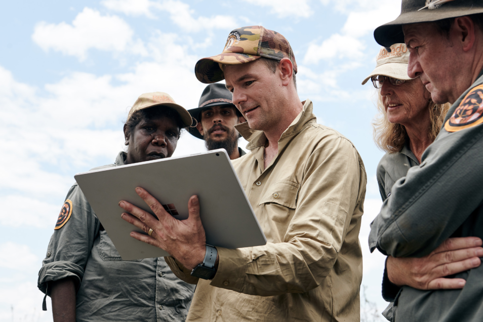Dr Justin Perry looking at an Ipad with Indigenous rangers