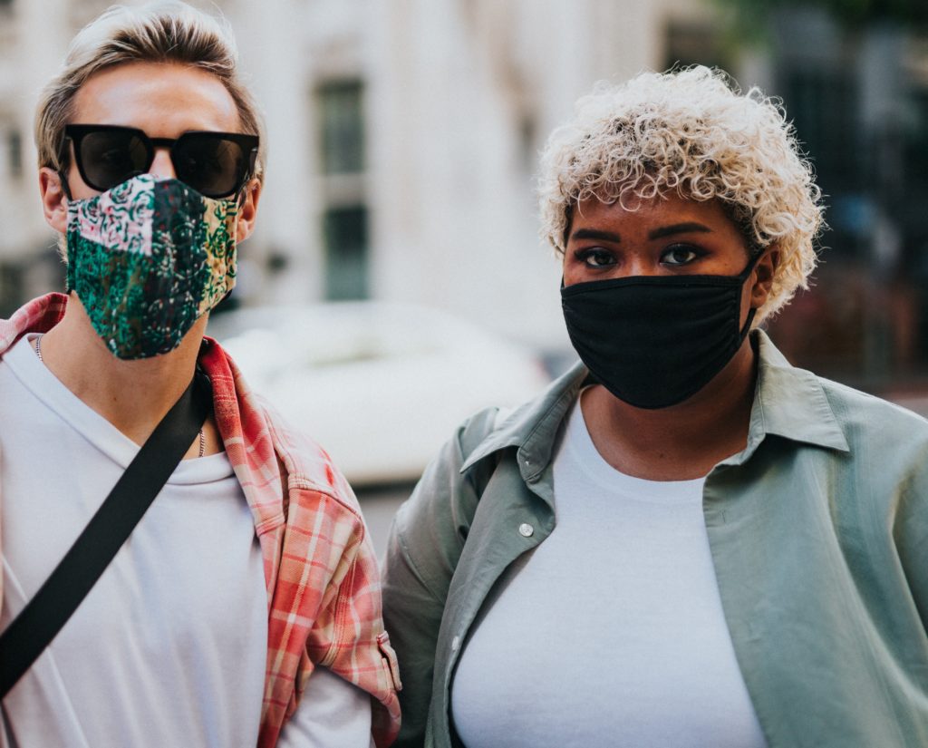 two people standing outside with masks on