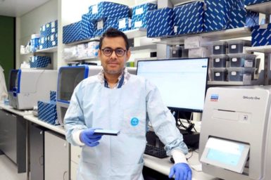 A man wearing full lab gear smiling at the camera.