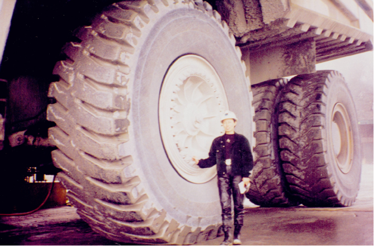 Helen standing with a 793b truck in her engineering career