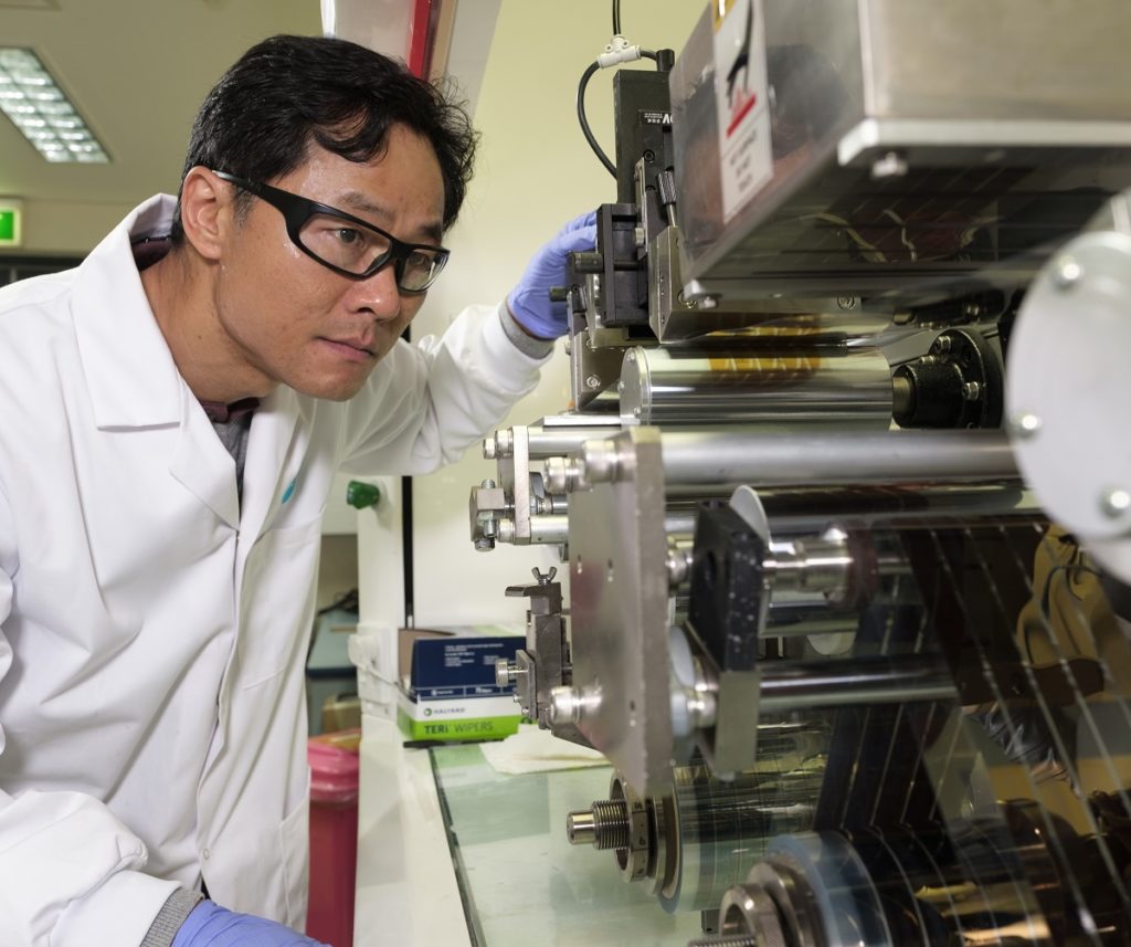 Dr Doojin Vak with safety glasses onlooking at the machine that prints flexible solar panels.