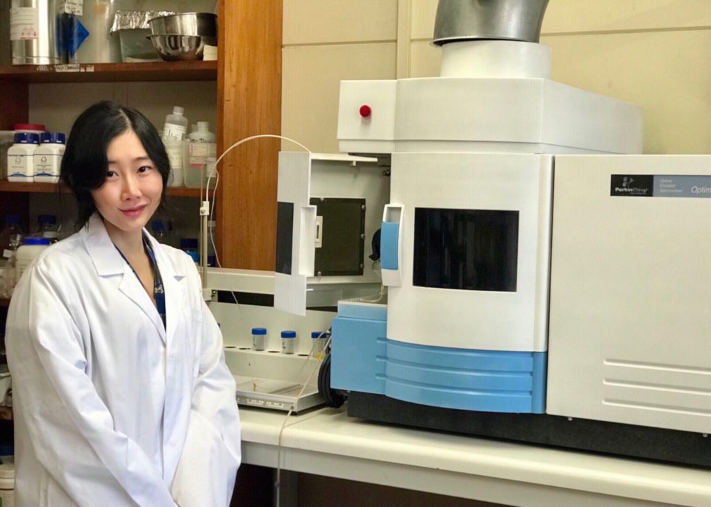 Image of a researcher standing in front of scientific equipment.