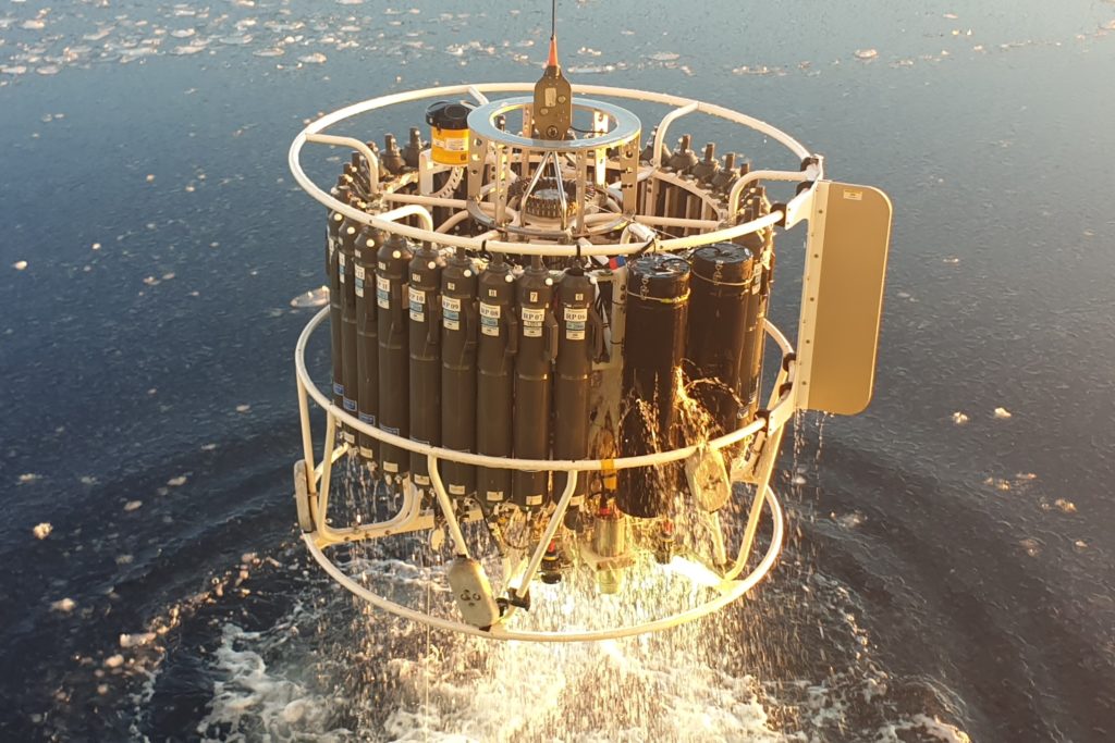 Circular arrangement of bottles being lifted from the ocean by a cable. 