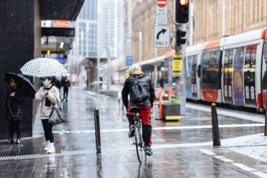A man riding his bike through a city street during wet weather