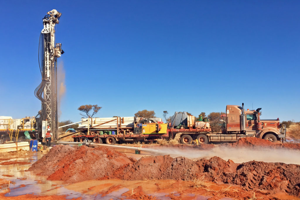 A photo of a truck with drilling equipment in the outdoors with a large blue sky in the background.