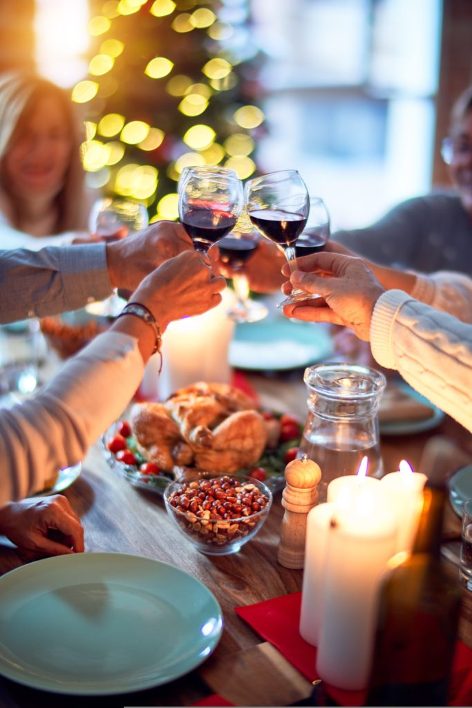 holiday season stress. Group of people 'cheers' glasses over Christmas lunch.