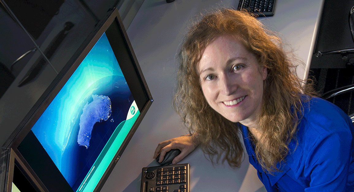 A woman smiling as she uses a computer