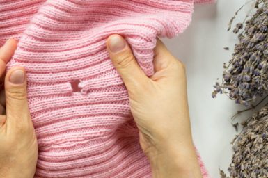 Pink jumper being held to reveal a hole.