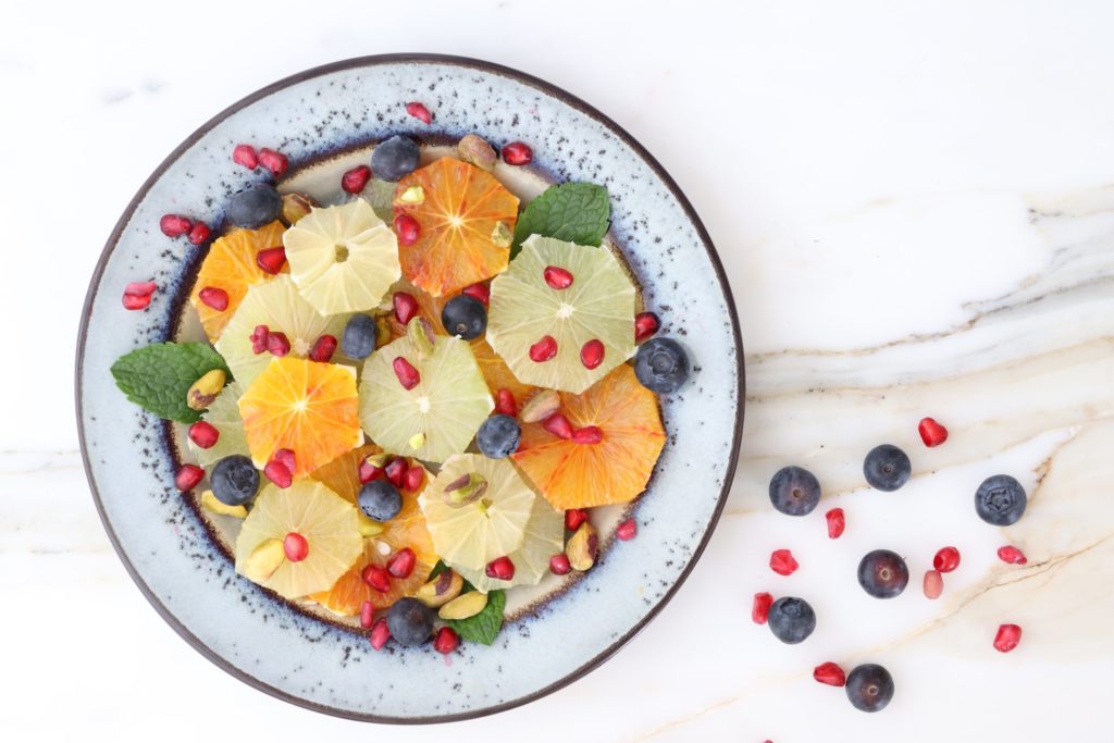 A fruit salad including fruit like mandarins and watermelon can help trick your brain into eating healthy. This fruit salad contains oranges, blueberries and pomegranate. 