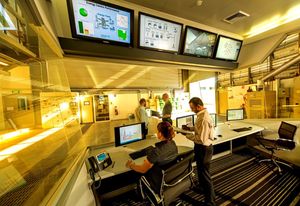 A photograph of a group of workers inside a lab with different computer screens.