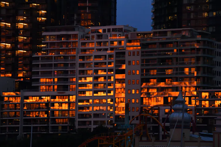 An apartment building with the sun set reflecting in the windows.