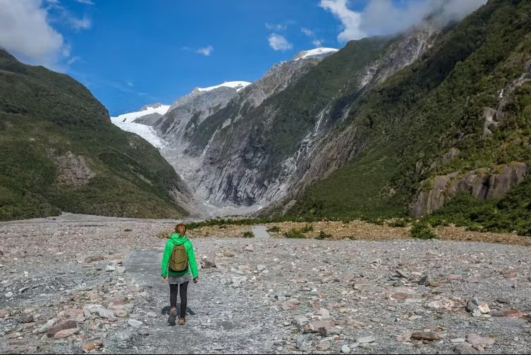 A woman hiking at the Franz Josef glacier in New Zealand. Climate change weather