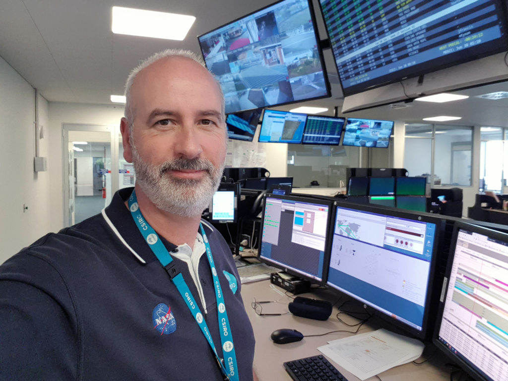 Richard Stephenson in the control room tracking james webb telescope with lots of monitor screens behind him