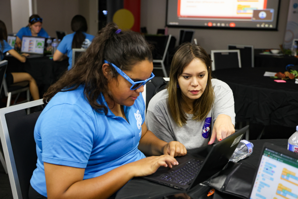 A student and mentor working together on a laptop