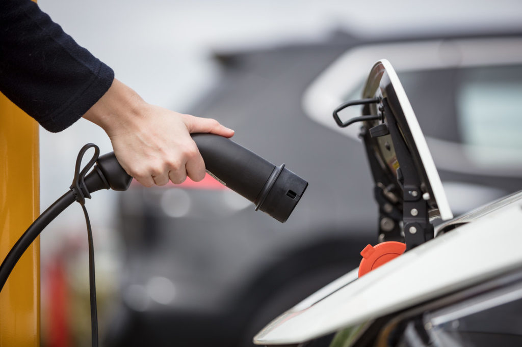 A close up of a hand charging an electric vehicle.