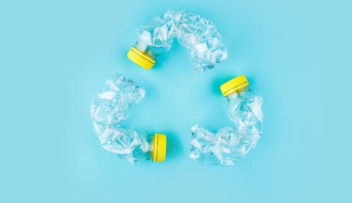 A photo showing three plastic bottles bent to form the shape of a recycling icon.